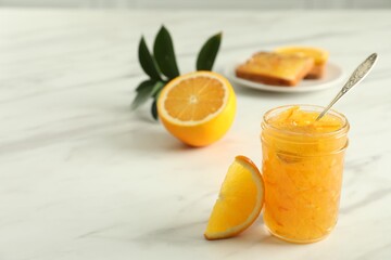 Delicious orange marmalade and citrus fruit slice on white marble table. Space for text