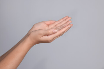 Woman stretching hands against light grey background, closeup. Space for text