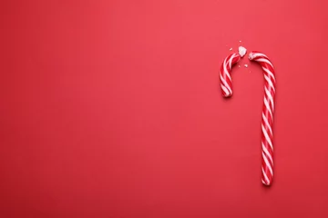 Poster Broken sweet Christmas candy cane on red background, top view. Space for text © New Africa