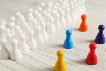 Colorful pawns on white wooden table, closeup. Social inclusion concept - obrazy, fototapety, plakaty
