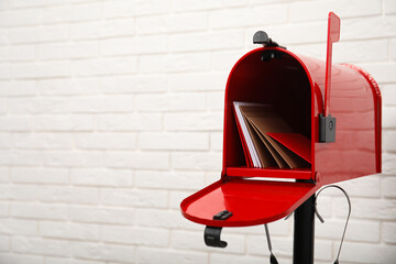 Open red letter box with envelopes near white brick wall. Space for text - Powered by Adobe