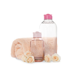 Obraz na płótnie Canvas Bottles of micellar cleansing water, rolled towel and flowers on white background