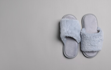 Pair of soft slippers on light grey background, top view. Space for text