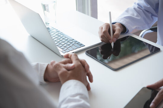 Doctor And Patient Talking At Medical Examination At Hospital Office, Close-up. Doctor Using Digital Tablet Filling Up Electronic Health Records And Prescription. Medicine And Healthcare Concept