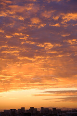 Fototapeta na wymiar 都会の夜明け。神戸市街地からの日の出。オレンジ色に染まる空と雲。神戸市街地から芦屋大阪方面を臨む