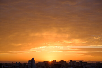 Fototapeta premium 都会の夜明け。神戸市街地からの日の出。オレンジ色に染まる空と雲。神戸市街地から芦屋大阪方面を臨む