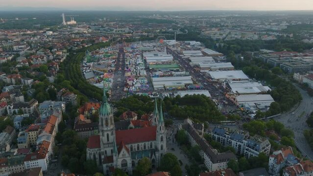 Aerial shot of crowded Theresienwiese, Oktoberfest grounds and surrounding town development at twilight. Famous and largest folk festival in world. Munich, Germany
