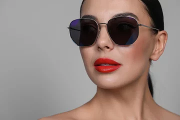 Attractive woman in fashionable sunglasses against grey background, closeup. Space for text © New Africa