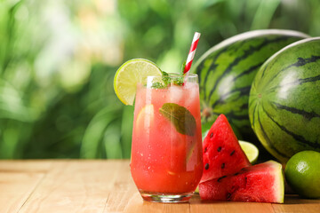 Glass of freshly made watermelon juice with lime and mint on wooden table outdoors