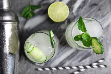 Glasses of refreshing cucumber water with ice grey on table, flat lay