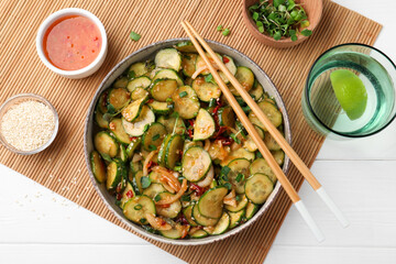 Bowl of delicious cucumber salad served on white wooden table, flat lay