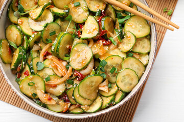Bowl of delicious cucumber salad served on white wooden table, top view