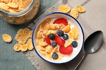 Delicious crispy cornflakes with milk and fresh berries on light blue wooden table, flat lay