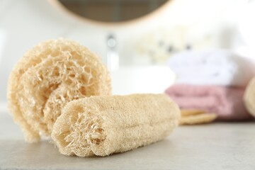 Fototapeta na wymiar Natural loofah sponges on table in bathroom, closeup. Space for text