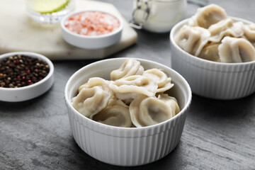 Tasty dumplings in bowls served on grey table