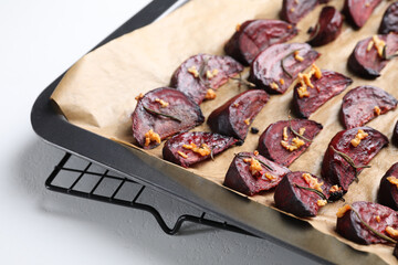 Baking tray with roasted beetroot slices on white table, closeup