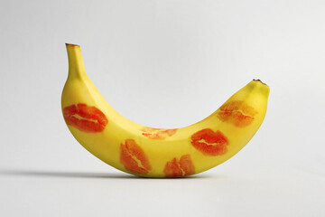 Banana covered with red lipstick marks on light grey background. Potency concept - obrazy, fototapety, plakaty
