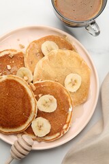 Tasty pancakes with sliced banana served on white marble table, flat lay