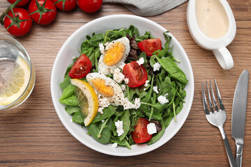Delicious salad with boiled egg, tomatoes and cheese served on wooden table, flat lay