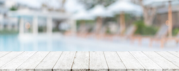 Empty wood table top and blurred swimming pool in tropical resort in summer banner background - can used for display or montage your products.