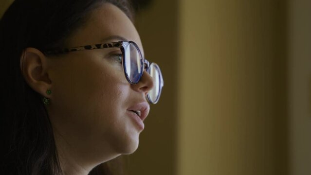 Close-up view of a woman in smart outfit and glasses in antique interior. Caucasian, adult lady in her 30s gives interview with a lavalier microphone on her clothes. Video recording. High quality 4k