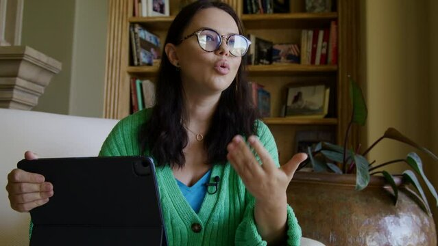 Close-up view of a woman in smart outfit and glasses in antique interior. Caucasian, adult lady in her 30s gives interview with a lavalier microphone on her clothes. Video recording. High quality 4k