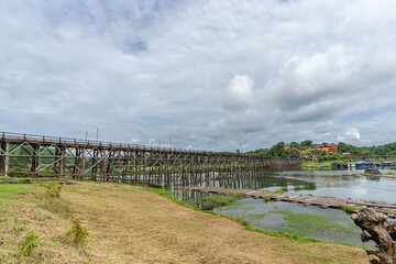 Fototapeta na wymiar Mon Bridge, wooden bridge over the river In Sangkhlaburi District, Kanchanaburi, natural attractions Landmark of Thailand