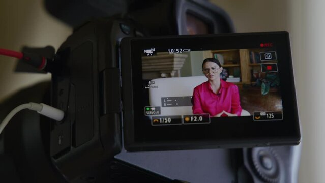 Close-up of caucasian, brunette woman in glasses within charming interior. Video recording of a lady in smart outfit as seen through camera screen. High quality 4k footage