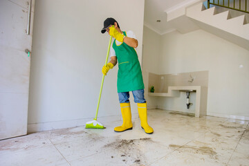 Male janitor clean floor with broom in dirty house