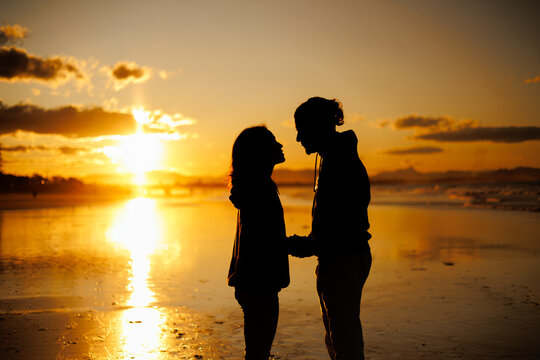 夕日のビーチで見つめ合うカップルのシルエット