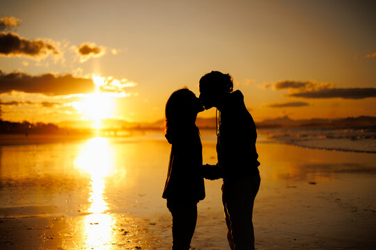 夕日のビーチでキスをするカップル