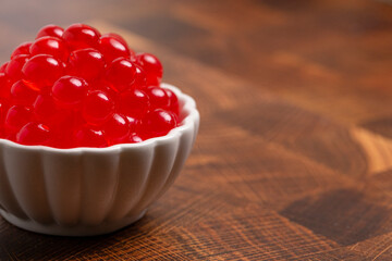 A Bowl Filled with Red Popping Boba on a Wood Background