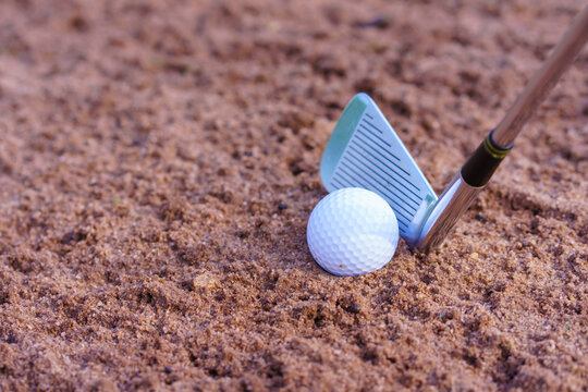 Golfer hitting out of a sand trap. The golf course is on the sand
