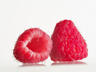 Close-up. On a white background, two berries of juicy ripe raspberries. Vitamins, antioxidants, healthy food, healthy lifestyle, sweet dessert. There are no people in the photo.