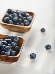 Blueberries in wooden bowls on a white background. Lots of objects. Low angle view. There are no people in the photo. Vitamins, antioxidants. Cooking. Healthy lifestyle. Banner, advertising.