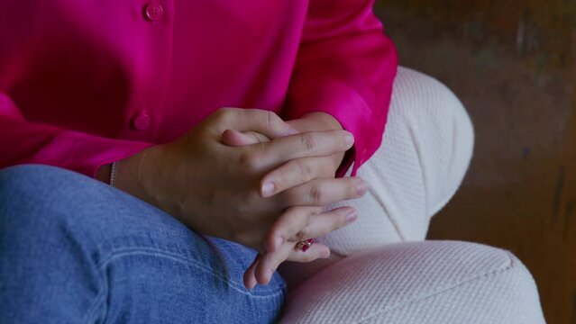 View on hands of a woman in smart outfit in antique interior. Caucasian, adult lady in her 30s gives interview with a lavalier microphone on her clothes. Video recording. High quality 4k
