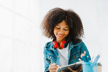 Young pretty african amerian woman studying online with laptop at living room.
