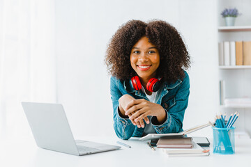 Young pretty african amerian woman studying online with laptop at living room.