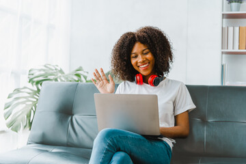 Young pretty african amerian woman studying online with laptop at living room.