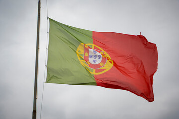 Waving flag of Portugal against clouded sky