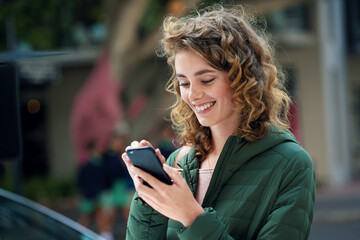 Happy woman, smile and typing on phone during travel in city using social media, internet and 5g network connection outside. Young female flirting on a mobile app for communication on urban street