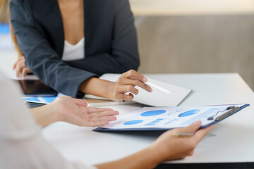 Business team jointly plan the investment at the meeting. Close-up of a business advisor pointing to graph and chart that analyze financial report, income statement, and company growth.