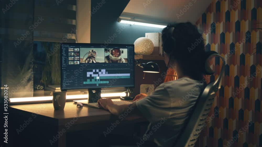 Poster man in headphones working remotely on pc from home office at night and editing video with astronauts