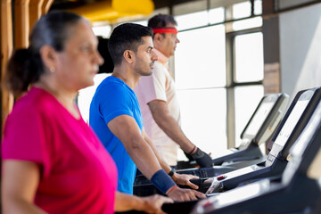 Fototapeta na wymiar Men and woman in sportswear doing cardio workout at gym 