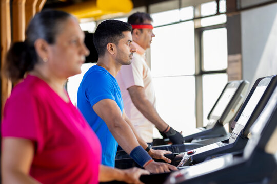 Men and woman in sportswear doing cardio workout at gym
