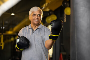 Senior male boxer training with punching bag
