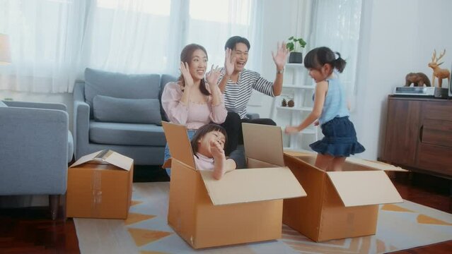 Asian family husband and wife and children with cardboard boxes having fun on moving day, Mortgage, loan, property and insurance concept.
