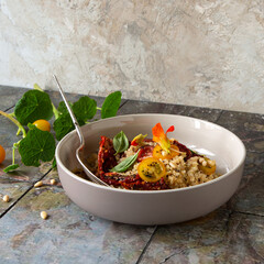 bowl with salad with quinoa, fresh tomatoes and sundried tomatoes on the table