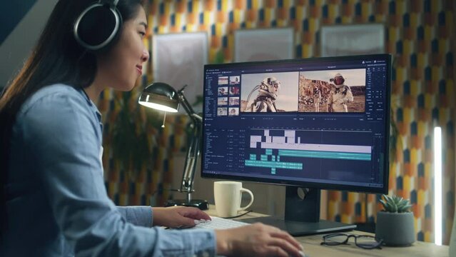 Asian woman in headphones working remotely on pc from home office and editing video with astronauts for customer in professional program