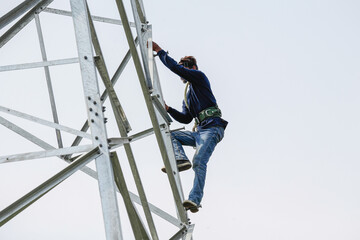Naklejka na ściany i meble Worker climbing on transmission line steel tower